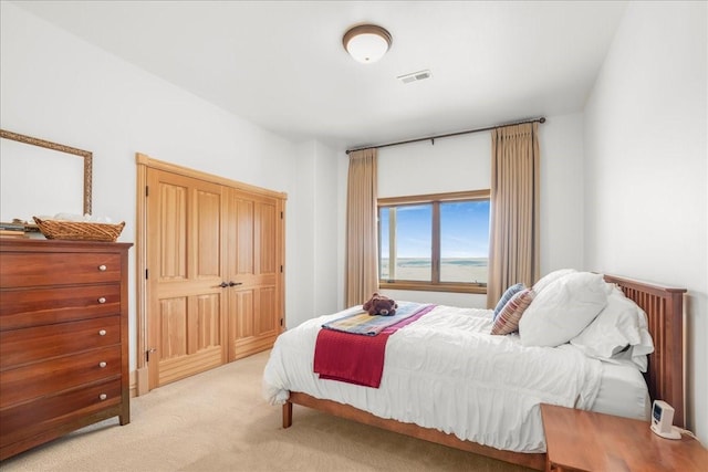 carpeted bedroom featuring visible vents and a water view