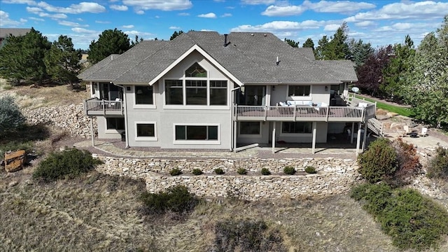 back of property featuring a shingled roof, a patio, stucco siding, and a deck