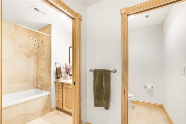 bathroom with vanity, tile patterned floors, toilet, tiled shower / bath combo, and visible vents