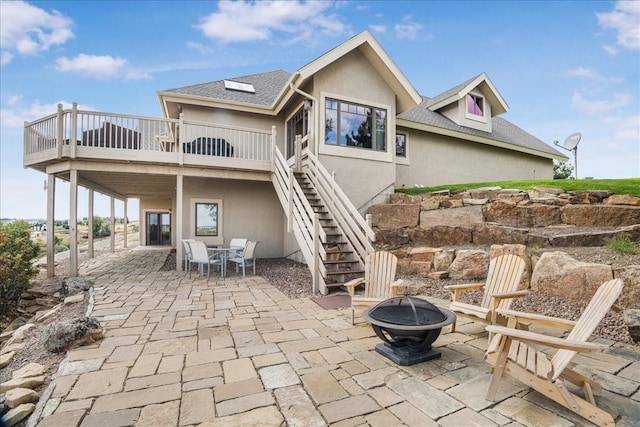 back of house featuring an outdoor fire pit, stucco siding, stairway, a patio, and a wooden deck