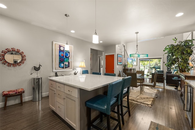 kitchen with dark hardwood / wood-style floors, a kitchen bar, a center island, and pendant lighting