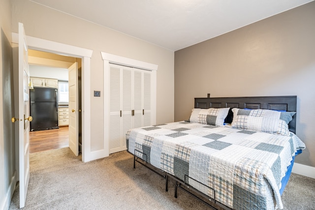 bedroom featuring light carpet, a closet, and black fridge