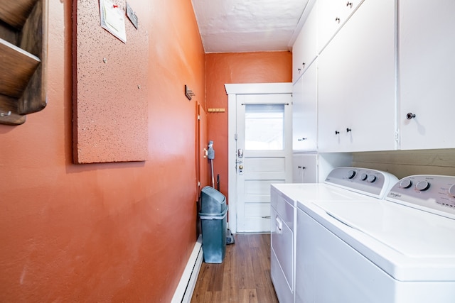 laundry room featuring washing machine and dryer, light hardwood / wood-style floors, a baseboard heating unit, and cabinets