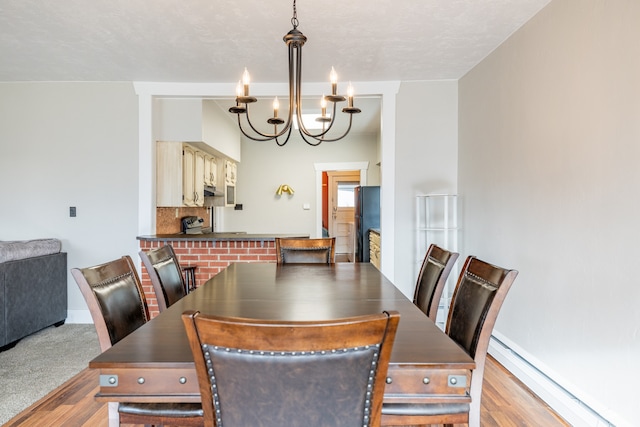 dining space with an inviting chandelier, light hardwood / wood-style floors, baseboard heating, and a fireplace