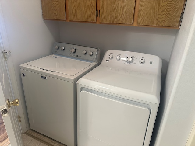 washroom featuring cabinets, washing machine and dryer, and light hardwood / wood-style flooring