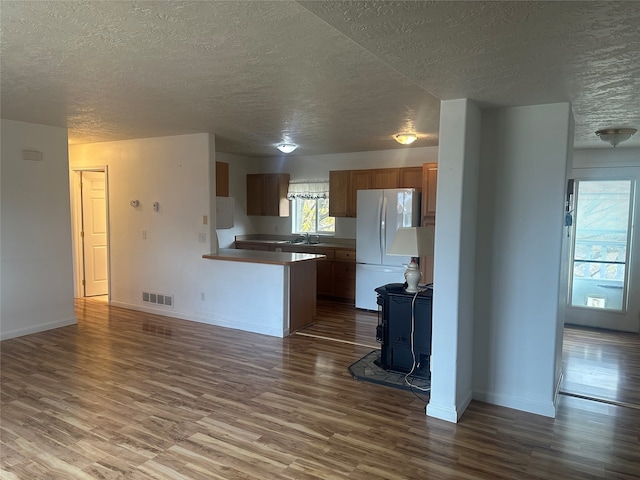 kitchen with a wood stove, hardwood / wood-style floors, a textured ceiling, and white fridge