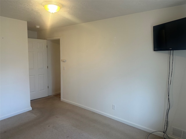 empty room featuring a textured ceiling and light carpet