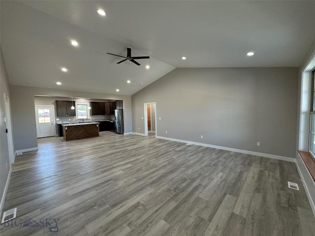 unfurnished living room with ceiling fan, light hardwood / wood-style flooring, and vaulted ceiling