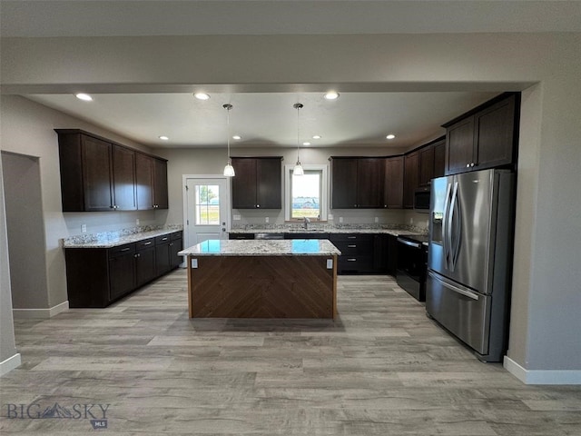 kitchen featuring dark brown cabinets, decorative light fixtures, appliances with stainless steel finishes, a center island, and light wood-type flooring