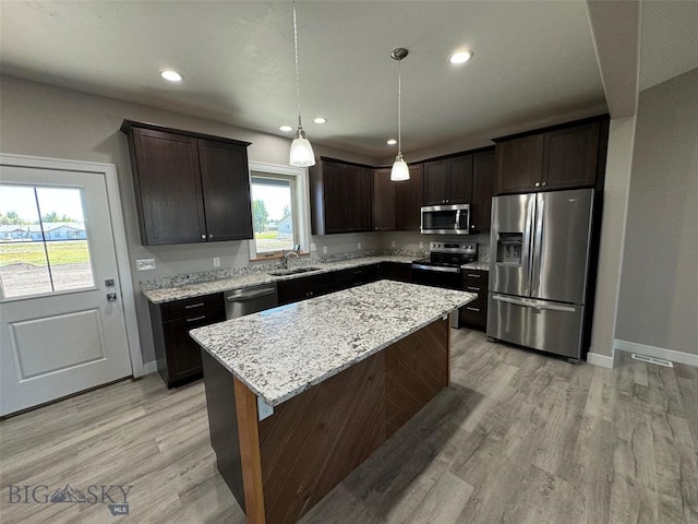 kitchen with decorative light fixtures, stainless steel appliances, a center island, and a wealth of natural light