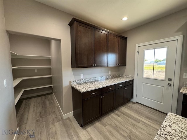 kitchen featuring light hardwood / wood-style floors, dark brown cabinets, and light stone counters