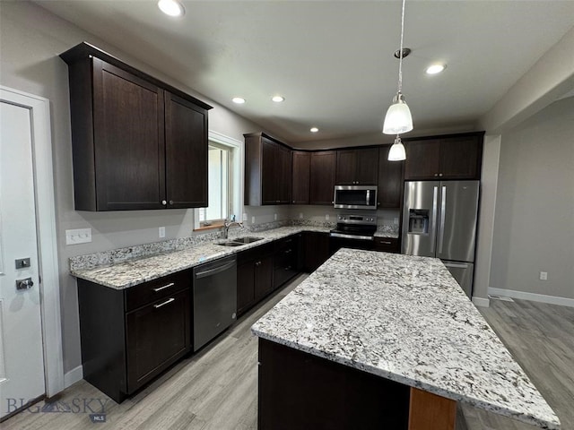 kitchen featuring pendant lighting, a center island, sink, light hardwood / wood-style flooring, and appliances with stainless steel finishes