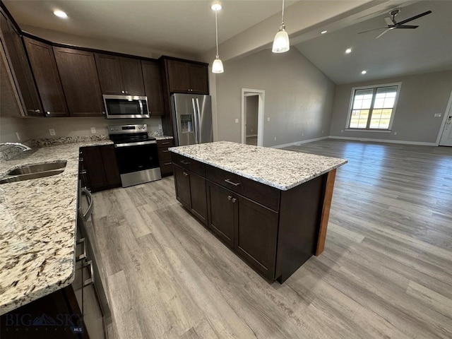 kitchen with light hardwood / wood-style floors, a kitchen island, vaulted ceiling with beams, appliances with stainless steel finishes, and ceiling fan