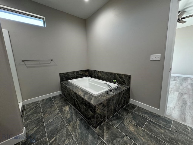 bathroom with ceiling fan and a relaxing tiled tub