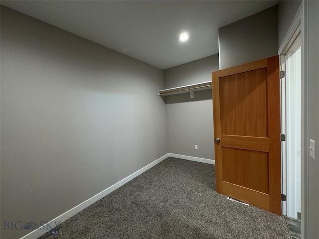 walk in closet with dark colored carpet