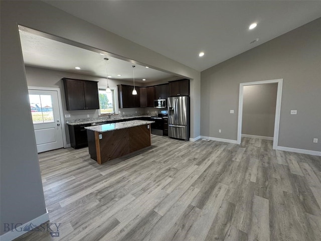 kitchen featuring pendant lighting, light hardwood / wood-style flooring, appliances with stainless steel finishes, a center island, and vaulted ceiling