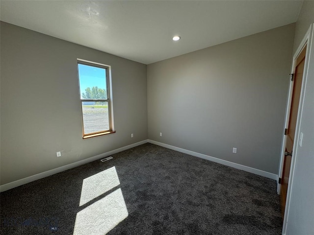 unfurnished room featuring dark colored carpet