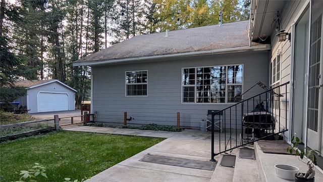 view of property exterior featuring a garage, a lawn, an outbuilding, fence, and a patio area