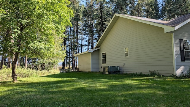 view of side of property with central AC and a yard