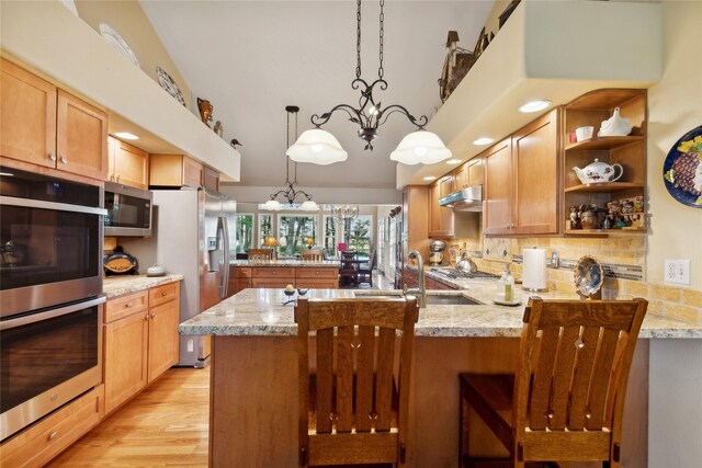 kitchen featuring tasteful backsplash, hanging light fixtures, kitchen peninsula, and light stone counters