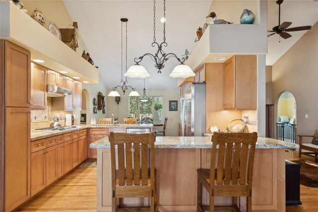 kitchen featuring light stone countertops, ceiling fan with notable chandelier, kitchen peninsula, and decorative light fixtures