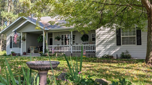 view of side of property featuring covered porch and a yard