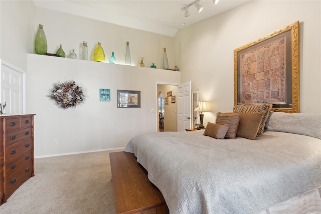 bedroom featuring baseboards, high vaulted ceiling, track lighting, and light colored carpet