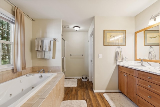 full bath featuring wood finished floors, vanity, visible vents, baseboards, and a whirlpool tub