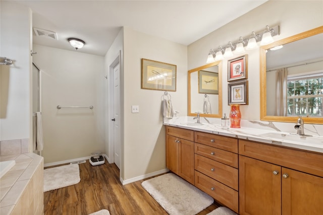 bathroom with tiled bath, hardwood / wood-style floors, and vanity