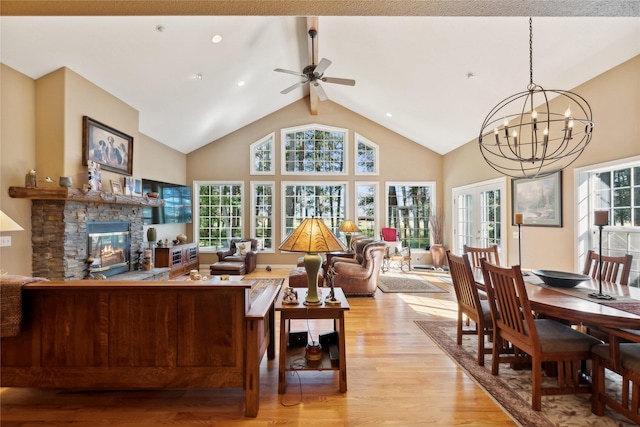 living area featuring high vaulted ceiling, a stone fireplace, french doors, light wood finished floors, and beamed ceiling