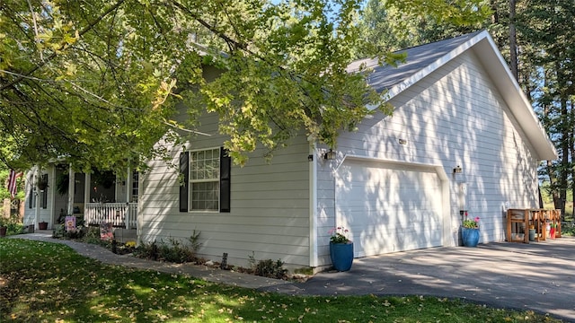 view of home's exterior featuring an attached garage, covered porch, and aphalt driveway