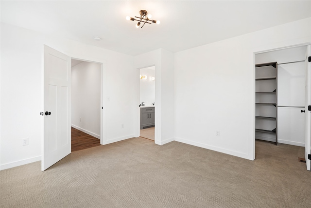 unfurnished bedroom featuring light colored carpet and connected bathroom