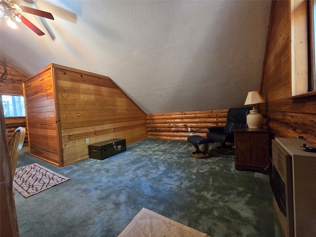 bonus room featuring a textured ceiling, wooden walls, vaulted ceiling, and ceiling fan