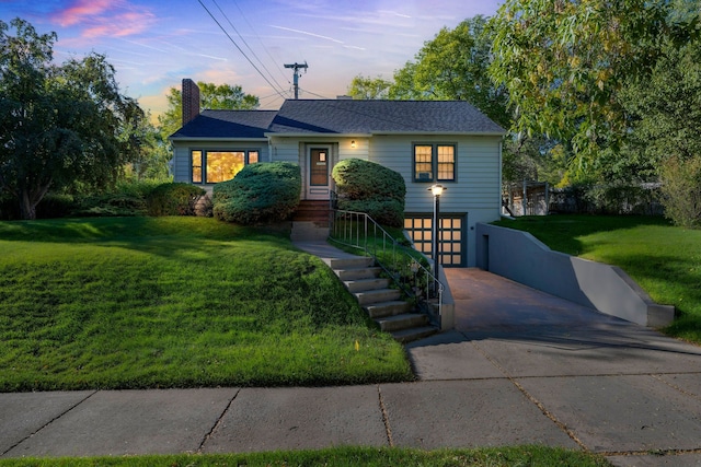 ranch-style home with a lawn, a chimney, an attached garage, and concrete driveway