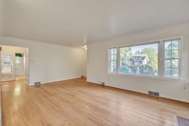 empty room with baseboards, visible vents, and light wood-type flooring