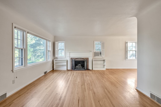 unfurnished living room with light wood-style flooring, baseboards, a fireplace, and visible vents
