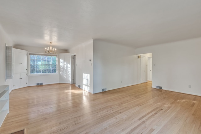 unfurnished living room featuring light wood-style flooring, visible vents, and an inviting chandelier