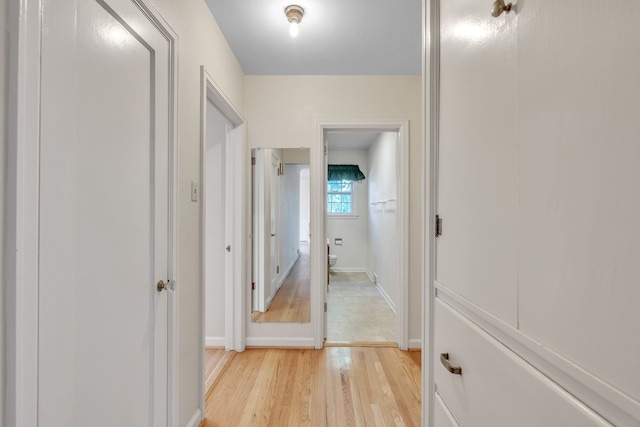 corridor featuring baseboards and light wood finished floors