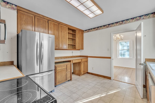 kitchen featuring a chandelier, open shelves, brown cabinetry, and freestanding refrigerator