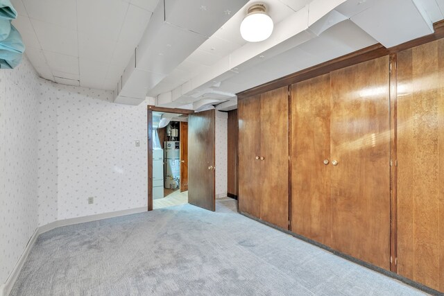finished basement featuring carpet flooring, wallpapered walls, and water heater