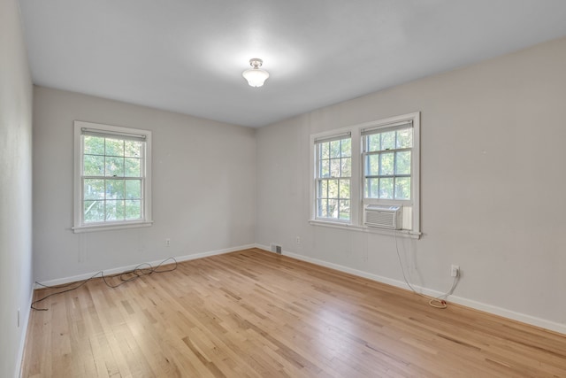empty room with baseboards, visible vents, light wood-style floors, and cooling unit