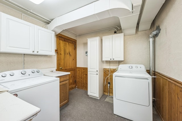 laundry area featuring washer and clothes dryer, wood walls, cabinet space, light carpet, and wainscoting