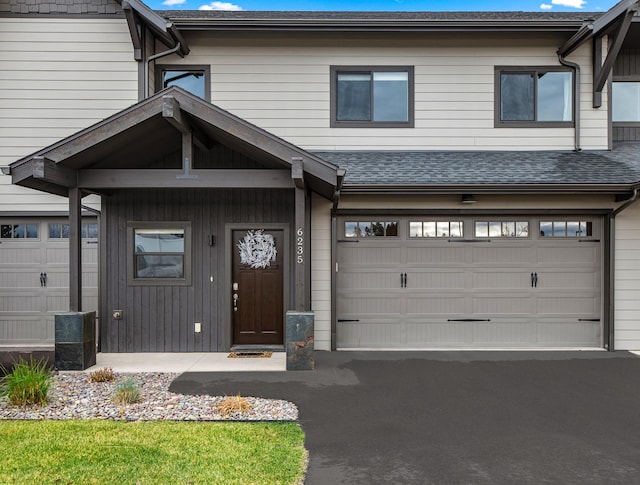 townhome / multi-family property featuring a garage, driveway, and roof with shingles