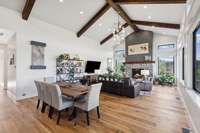 dining space with high vaulted ceiling, a wealth of natural light, light hardwood / wood-style floors, and a fireplace