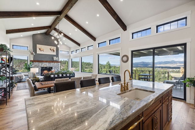 kitchen featuring high vaulted ceiling, light stone countertops, beam ceiling, light hardwood / wood-style flooring, and sink