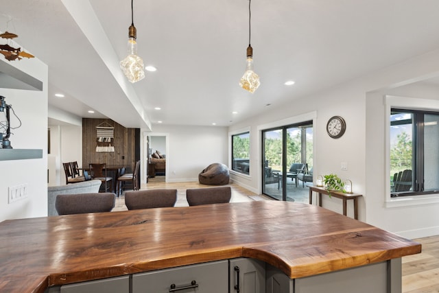 kitchen with pendant lighting, light hardwood / wood-style flooring, and wood counters