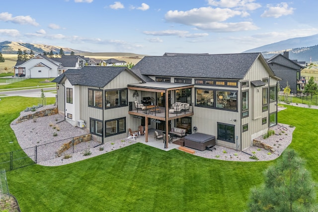 rear view of property with a mountain view, a lawn, and a patio