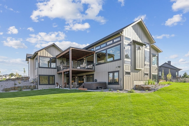 back of property with a yard, a hot tub, a balcony, and a patio area