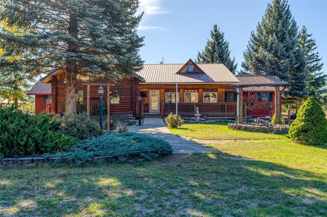 2237 Grave Creek Rd, Eureka, MT 59917 - view of front of property featuring a front yard, a metal roof, a porch, and log exterior