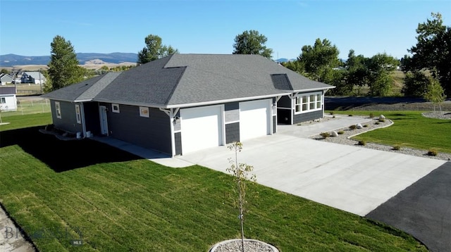 back of property featuring a mountain view, a garage, and a yard